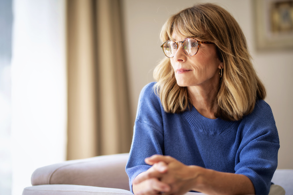 Eine Frau mit Brille und blauem Pullover auf dem Sofa