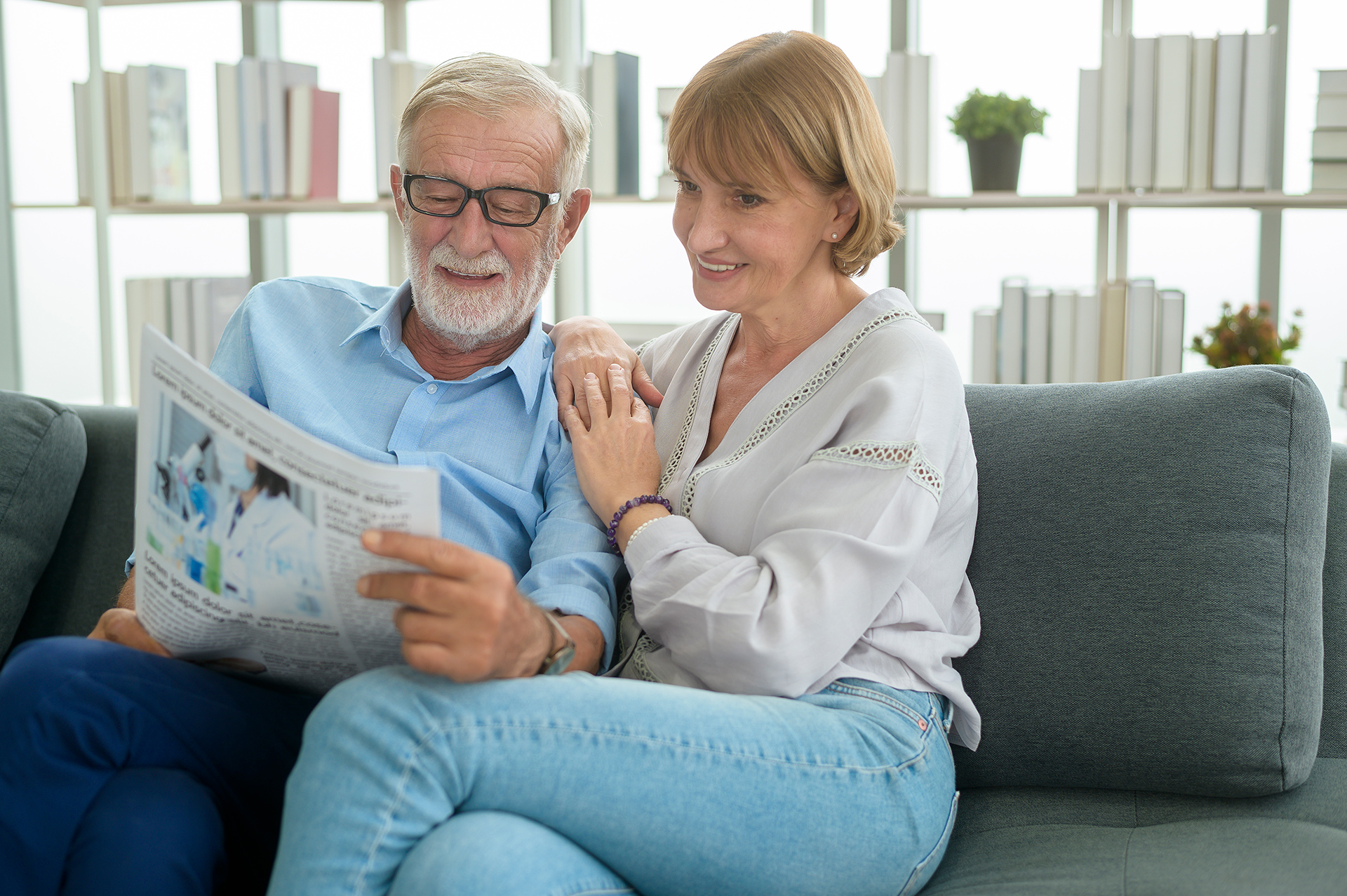 Ein älteres Paar sitzt auf dem Sofa und liest die Zeitung