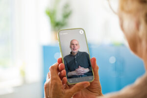 Ältere Frau hält ihr Smartphone in der Hand und schaut ein Video an.