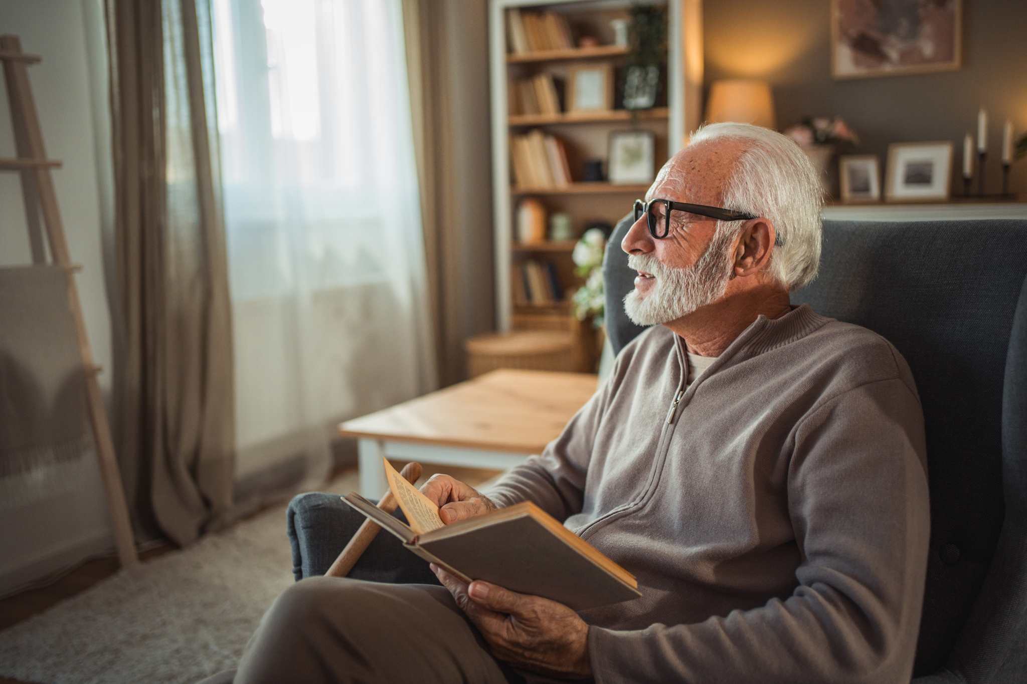 Älterer Mann mit Brille und weißen Haaren liest ein Buch