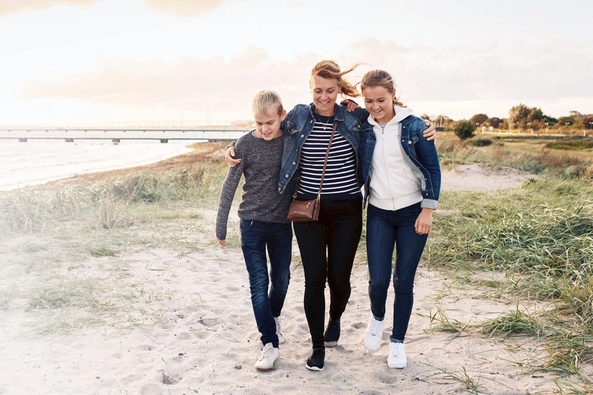 Eine Mutter läuft mit Ihren Kindern an den Dünen entlang