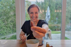 Tanja Multinu hält eine Dattel in die Kamera und sitzt vor einer Schüssel am Esstisch