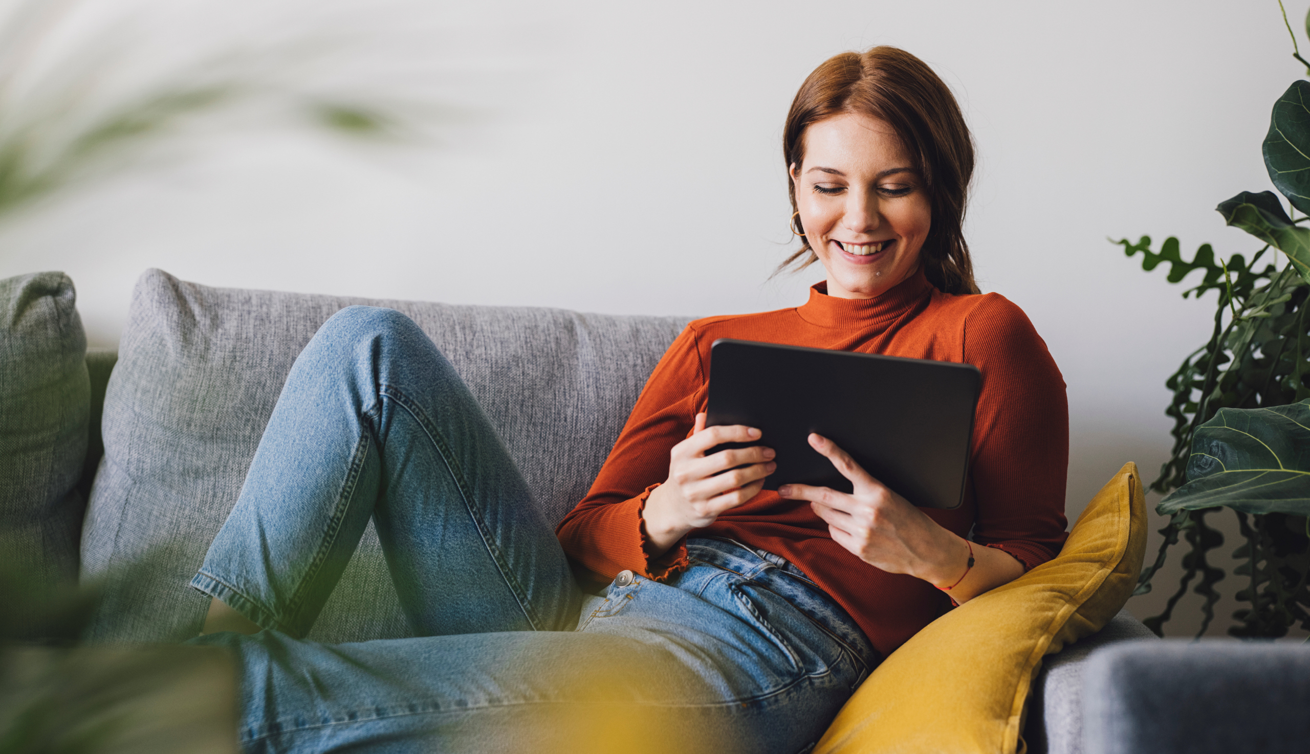 Eine junge Frau sitzt auf dem Sofa und führt einen Rheuma-Selbsttest durch.