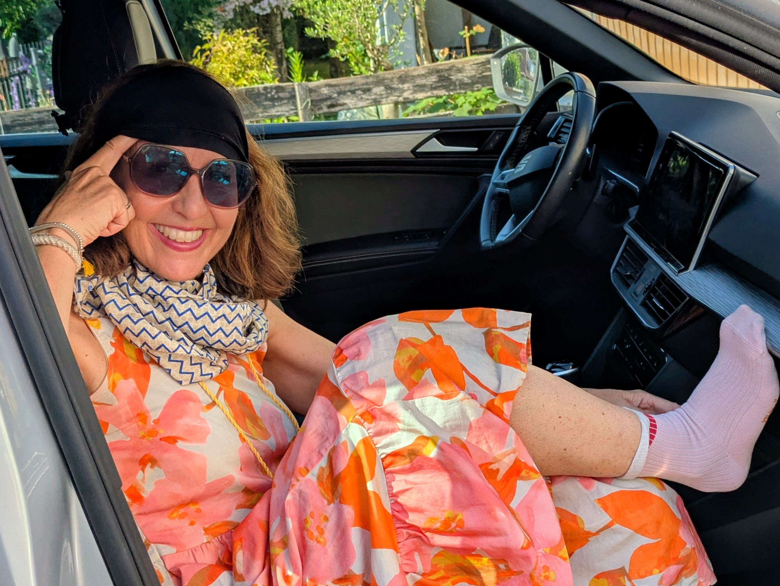 Lächelnde Frau mit Sonnenbrille und Stirnband bei einer Reisepause im Auto