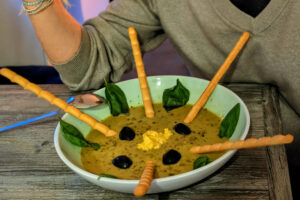 Frau hebt einen Löffel und isst Suppe.