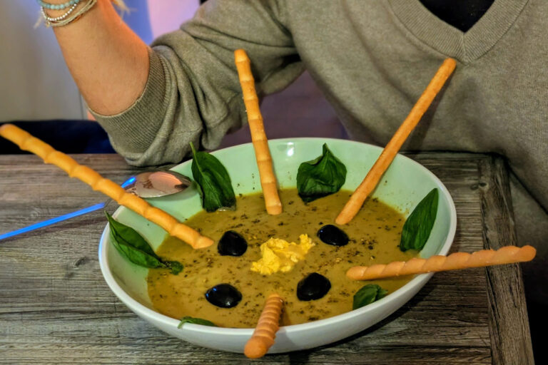 Frau hebt einen Löffel und isst Suppe.