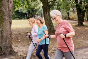 Drei Seniorinnen beim Nordic-Walking im Park